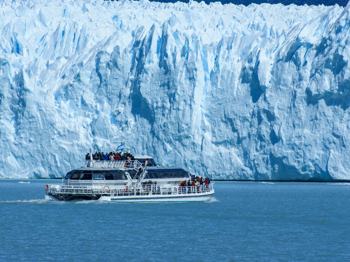 Tourists on a boat crossing the water in front of Perito Moreno Glacier's ice front