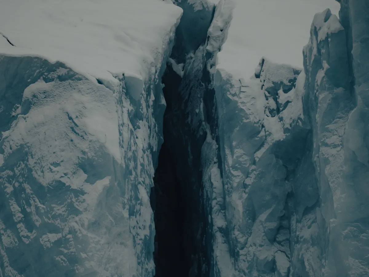 A deep blue crevasse cutting through glacier ice